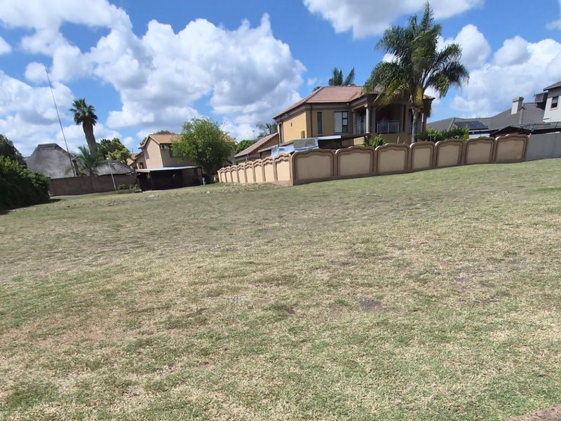 A vacant residential plot featuring a grass lawn and established boundary walls in a developed neighborhood setting.