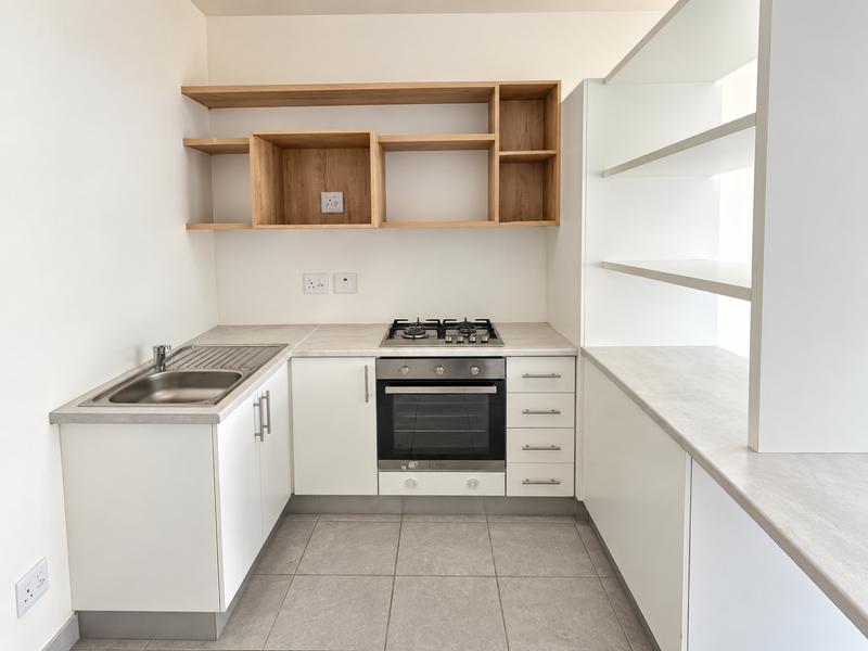 A clean, modern kitchen featuring white cabinetry, light wood open shelving, a built-in oven with gas hob, and neutral tiled flooring.