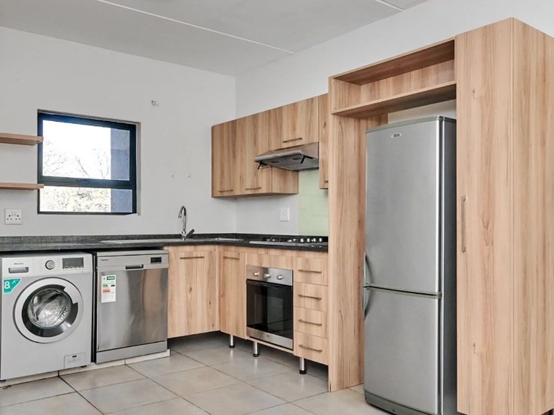 Modern kitchen featuring light wood cabinetry, granite countertops, integrated stainless steel appliances, and tiled flooring.