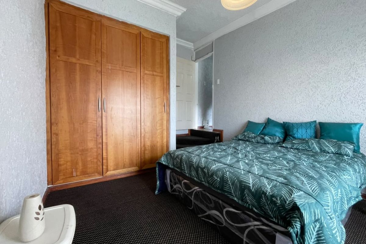 A bedroom featuring built-in wooden wardrobes, textured wall finishes, and carpet flooring, offering a functional space with classic design elements.