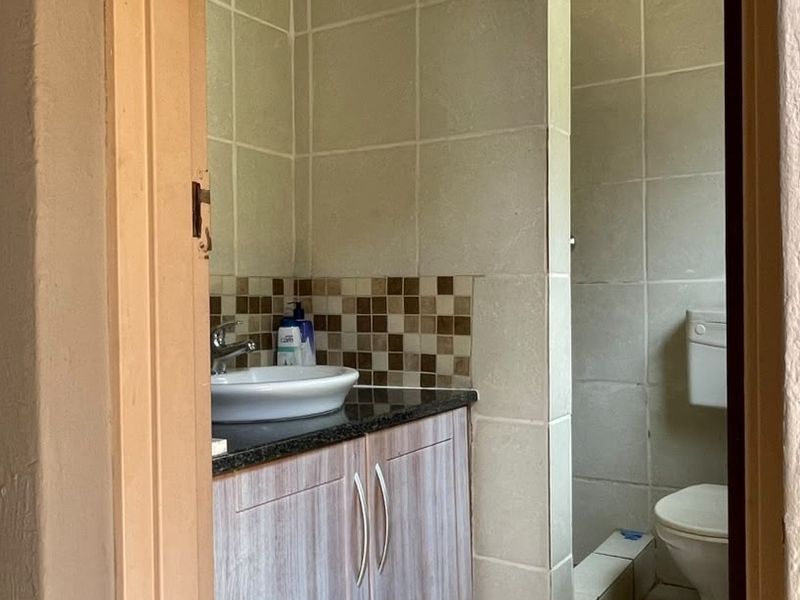 A functional bathroom featuring a vanity with a vessel sink, granite countertop, mosaic backsplash, and a separate tiled shower area.