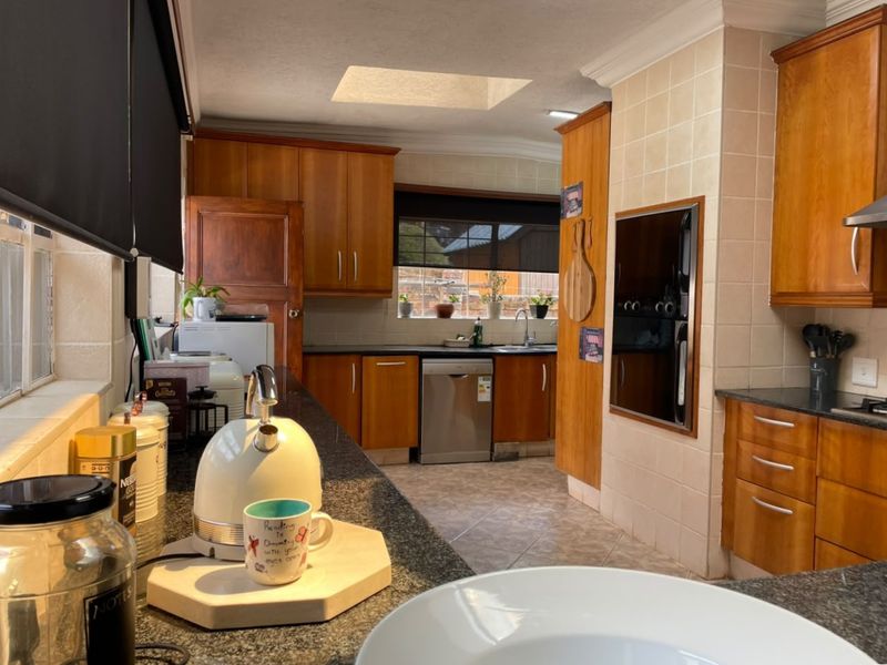 A functional kitchen featuring warm wooden cabinetry, granite countertops, a built-in oven, and a skylight providing natural light.