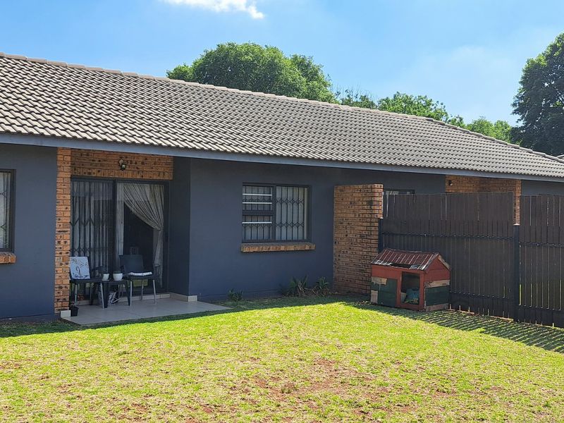 Rear view of the townhouse featuring a private garden, covered patio area, and secure timber fencing.