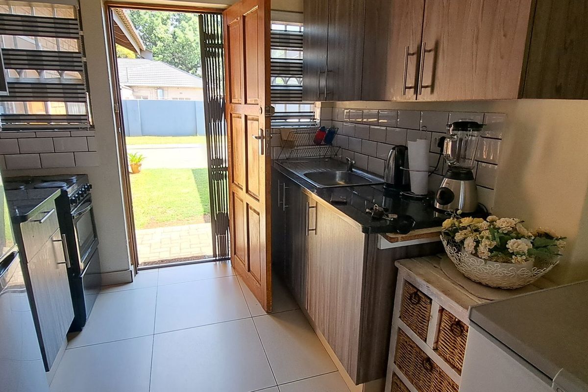 Compact kitchen featuring modern wood-finish cabinetry, subway tile backsplash, and direct access to the outdoor area through a security gate.