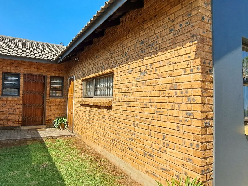 A view of the rear exterior of the townhouse featuring face brick walls, a tiled roof, and a small private garden area.