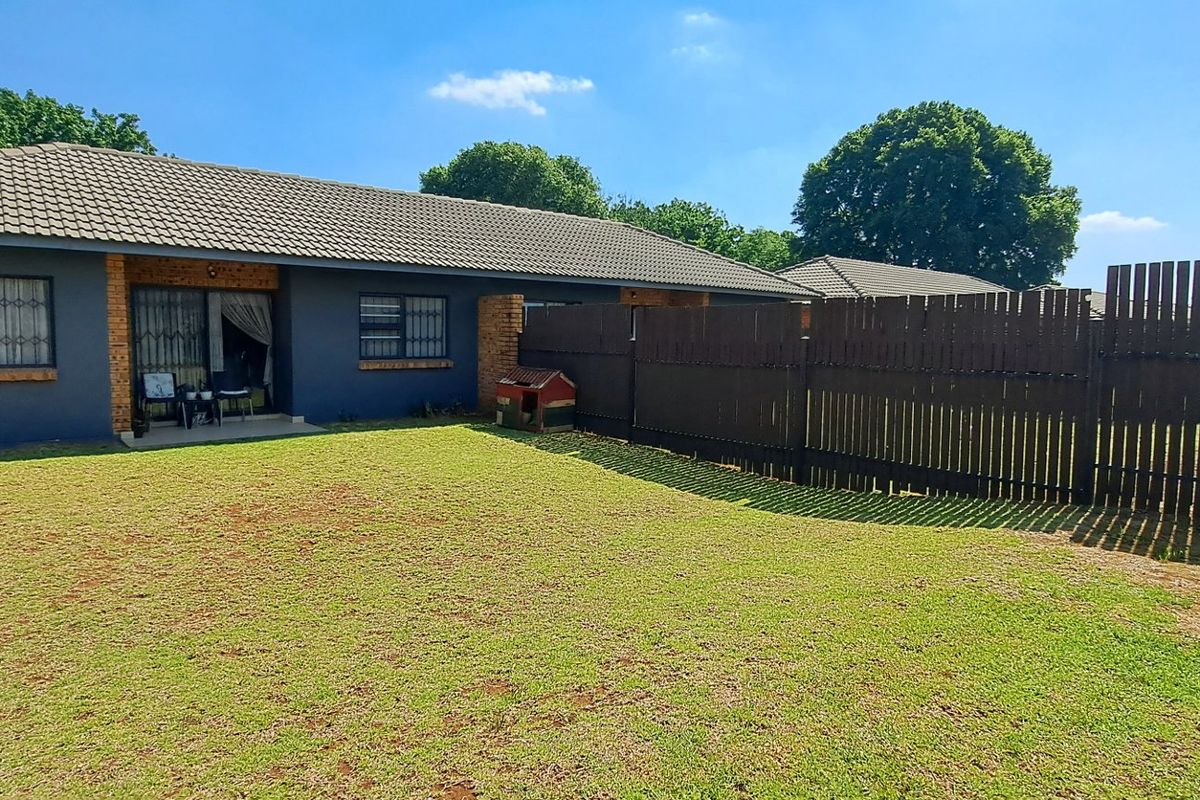 Rear view of the townhouse featuring a private garden, concrete patio area, and secure timber fencing.