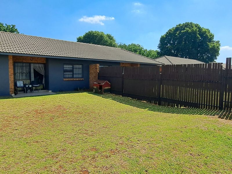 Rear view of the townhouse featuring a private garden, concrete patio area, and secure timber fencing.