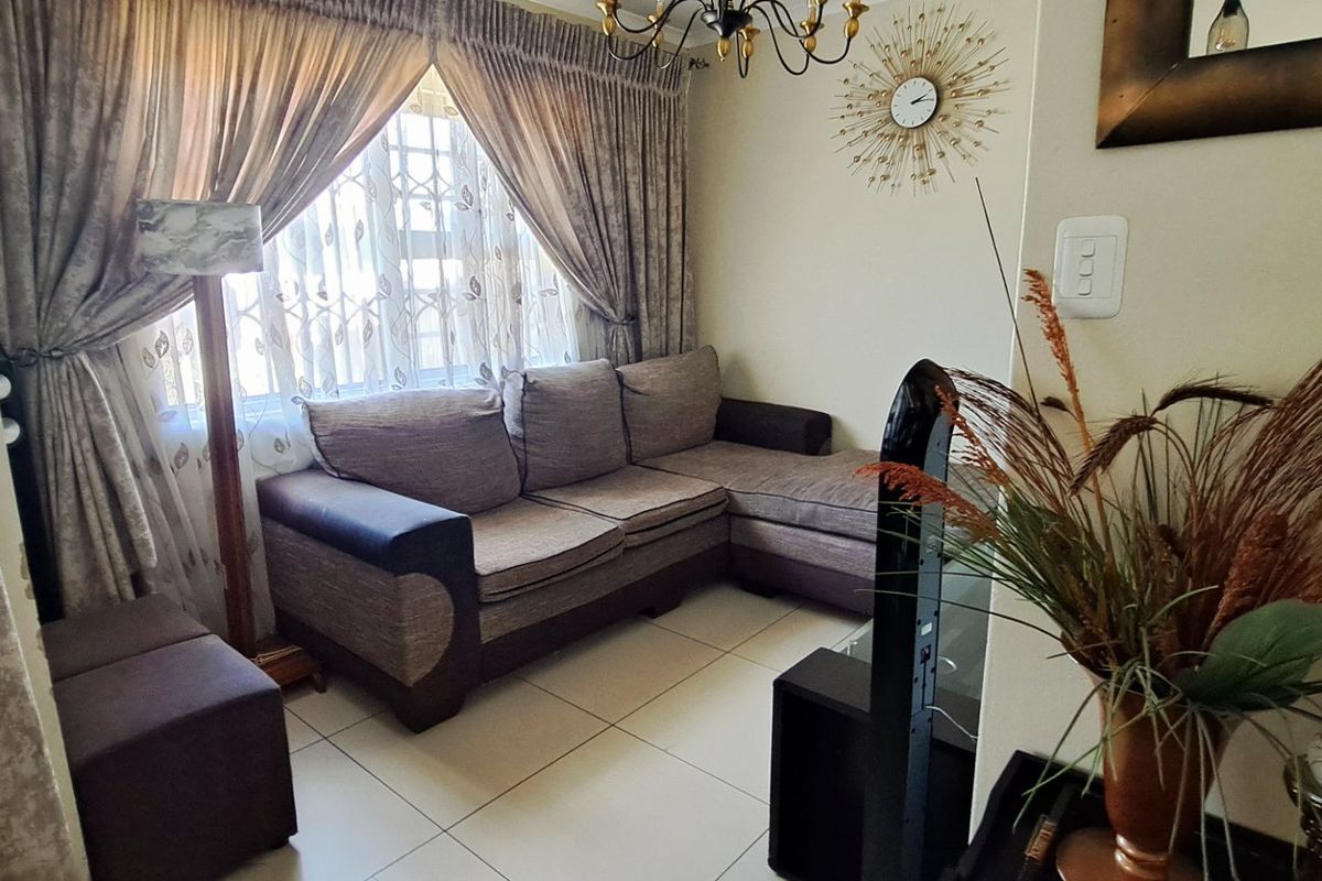 A cozy living room featuring tiled flooring and a window fitted with security bars, providing a functional and comfortable living space.