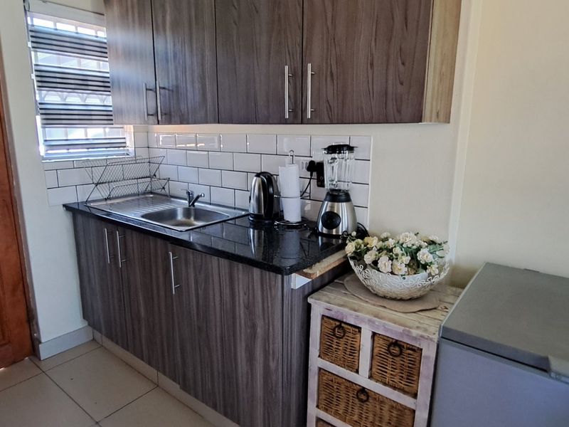 Compact kitchen featuring modern wood-look cabinetry, granite countertops, and a classic white subway tile backsplash.