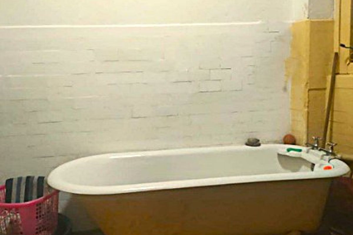 A bathroom featuring a vintage clawfoot bathtub against a partially finished wall, requiring renovation to improve the overall condition and aesthetic appeal.
