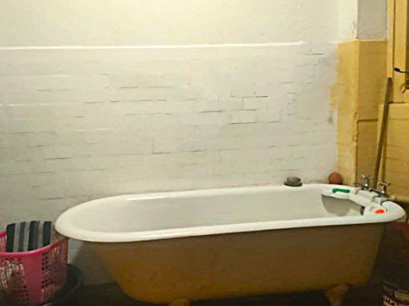 A bathroom featuring a vintage clawfoot bathtub against a partially finished wall, requiring renovation to improve the overall condition and aesthetic appeal.