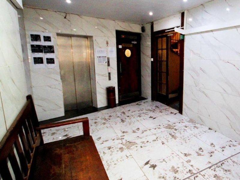 Apartment building entrance lobby featuring an elevator, marble-effect wall tiling, and recessed ceiling lighting.