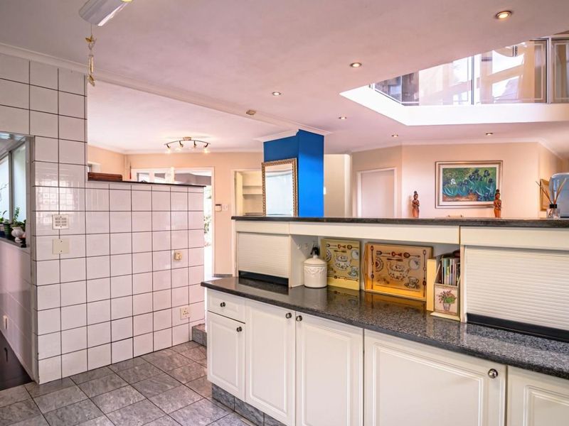 Open plan kitchen area featuring granite countertops, built-in cabinetry, and a large skylight providing ample natural light to the living space.