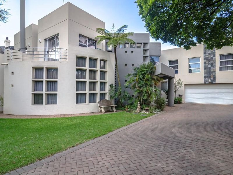 Modern architectural front elevation featuring a paved driveway, double garage, and a distinctive multi-pane window design with an upper-level balcony.