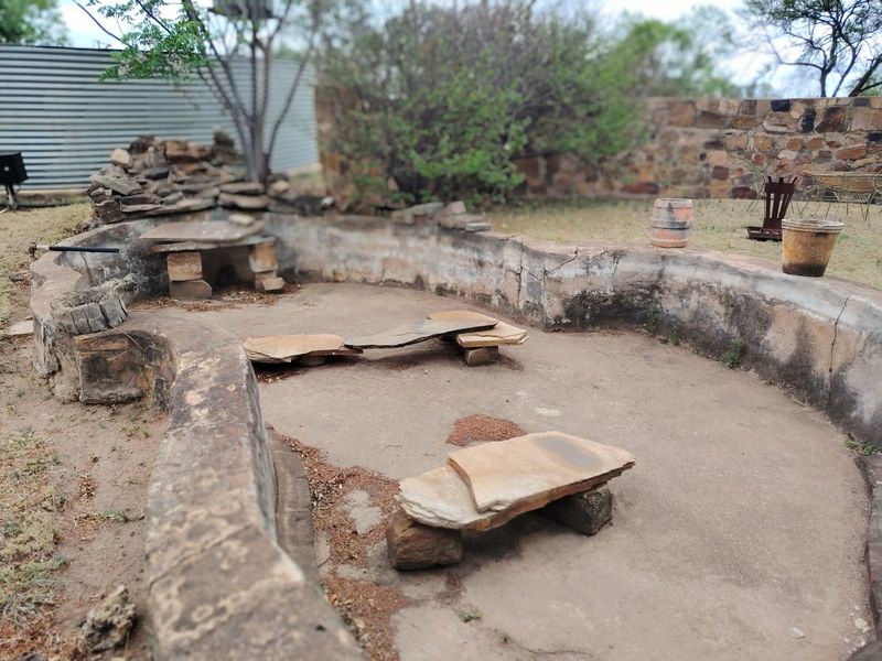 Outdoor garden area featuring stone retaining walls and integrated stone seating, requiring maintenance and landscaping improvements.