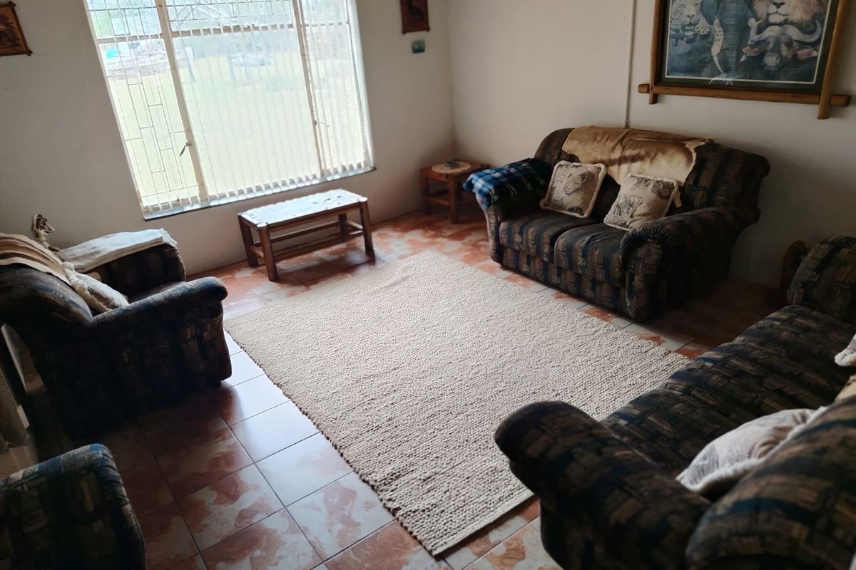 A living room featuring tiled flooring and a large window with security bars, offering a functional space with natural light.