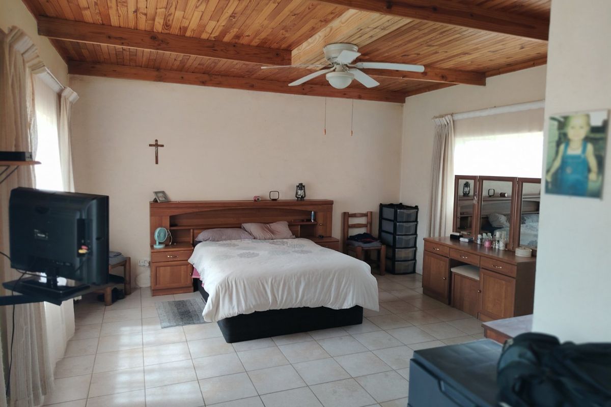Spacious bedroom featuring a timber tongue and groove ceiling with exposed beams, a ceiling fan, and neutral tiled flooring.