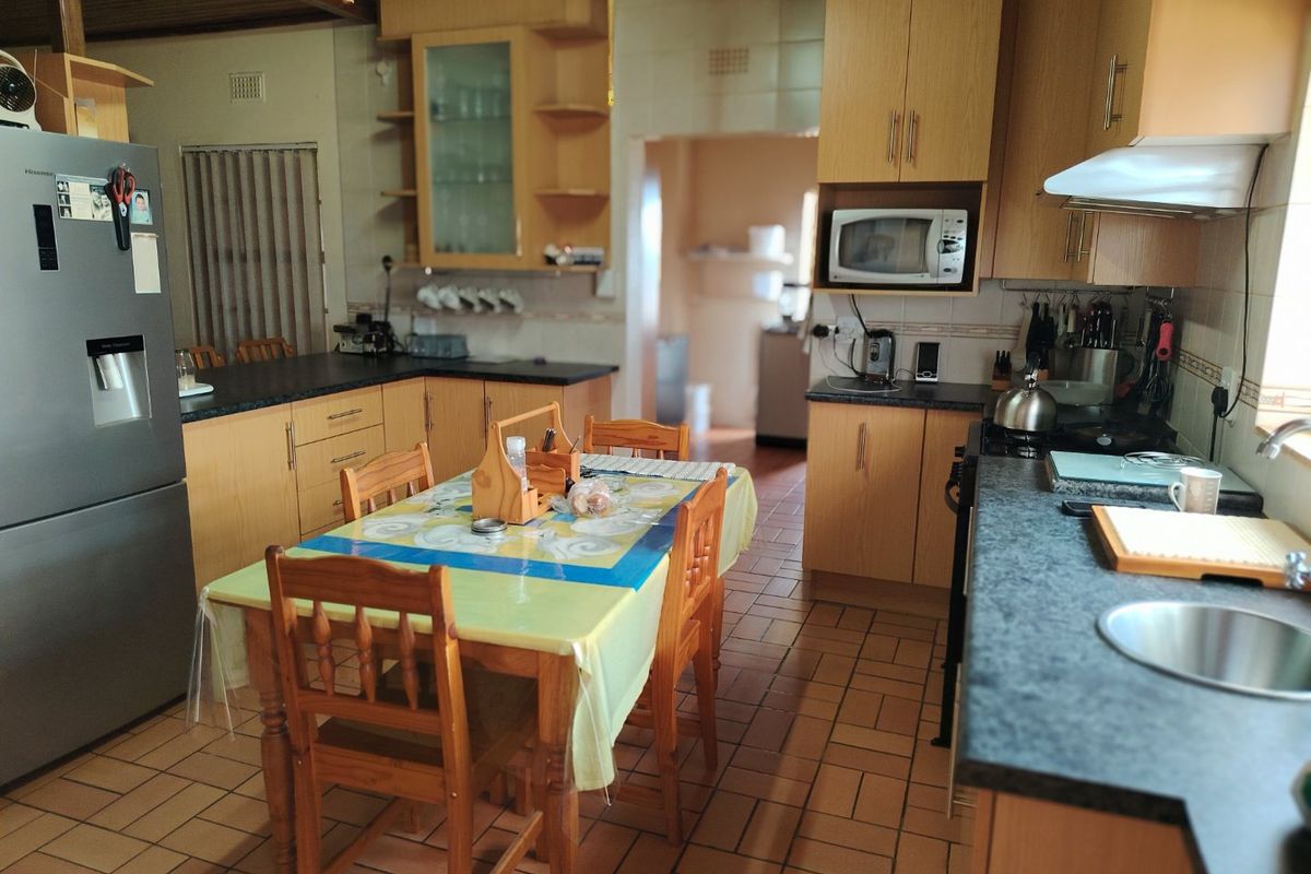A functional kitchen featuring wooden cabinetry, laminate countertops, tiled flooring, and integrated appliances, offering a practical layout for daily meal preparation.