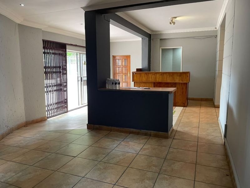 Commercial entry area featuring a built-in reception counter, ceramic tiled flooring, and a secure sliding glass door entrance.