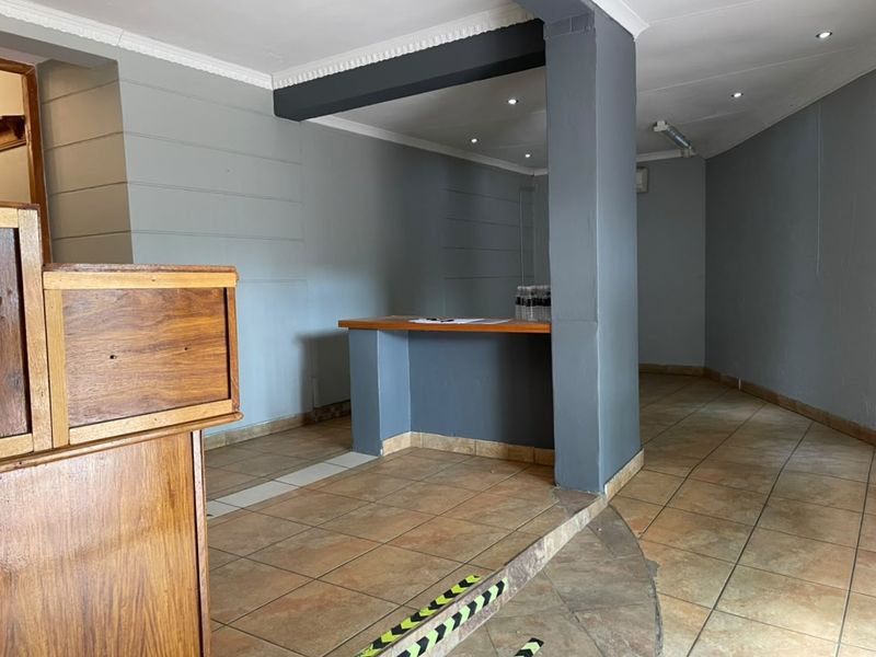 An open-plan commercial space featuring tiled flooring, a built-in service counter, and recessed lighting, suitable for various retail or office applications.