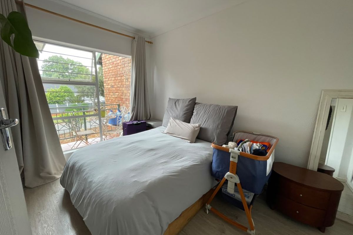 A bedroom featuring laminate flooring and a large sliding window with access to an outdoor balcony area.