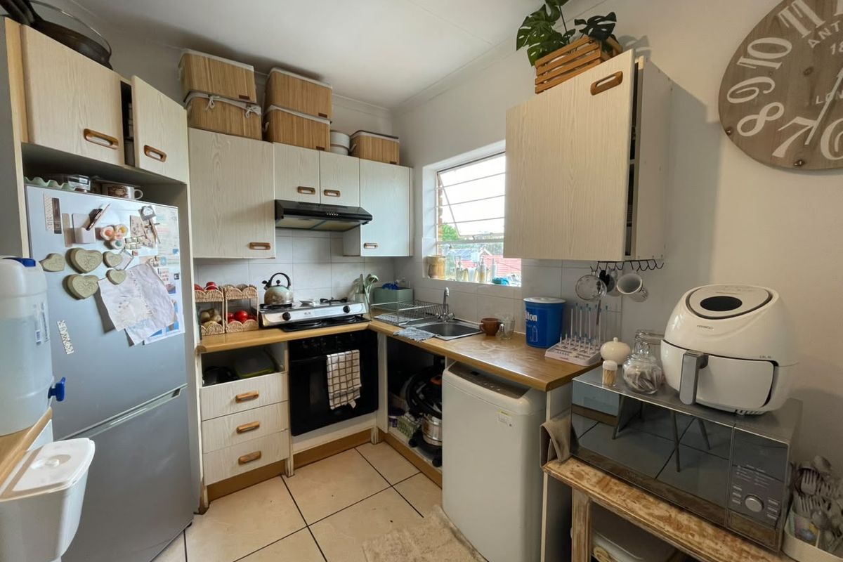 Compact kitchen featuring built-in cabinetry, laminate countertops, a gas hob with extractor fan, and tiled flooring, offering a functional layout for daily use.