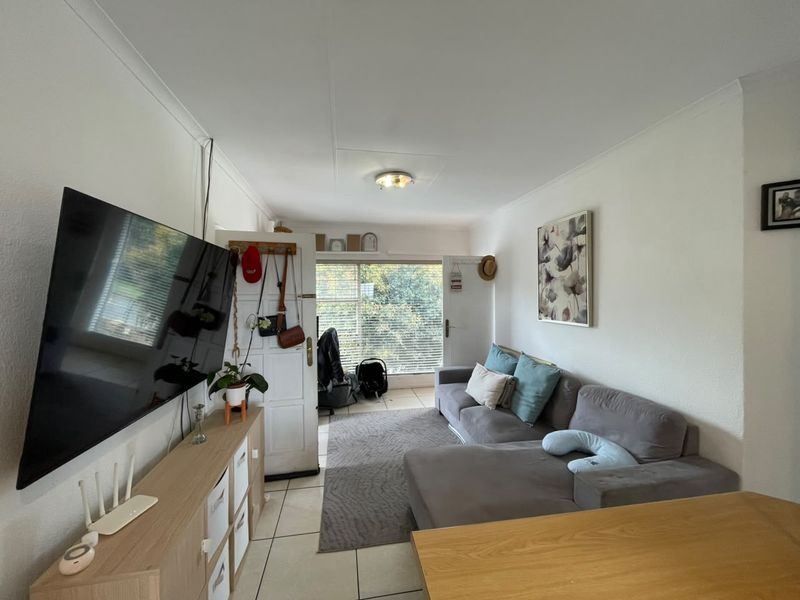 A functional living room featuring tiled flooring, coved ceilings, and natural light through window blinds, providing a comfortable and practical living space.