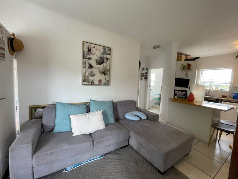 Open plan living area featuring a breakfast bar, tiled flooring, and a functional kitchen layout, providing a comfortable and connected living space.