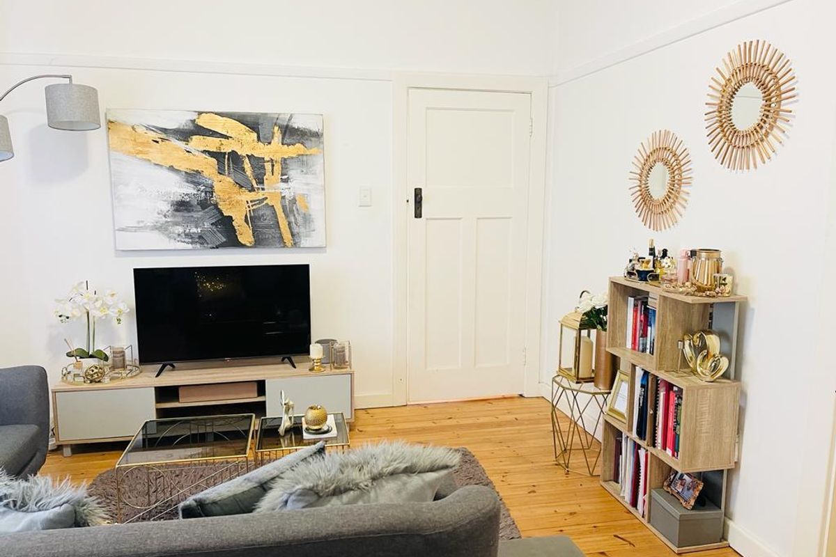 A well-maintained living room featuring polished timber flooring, classic picture rails, and a traditional panelled door.