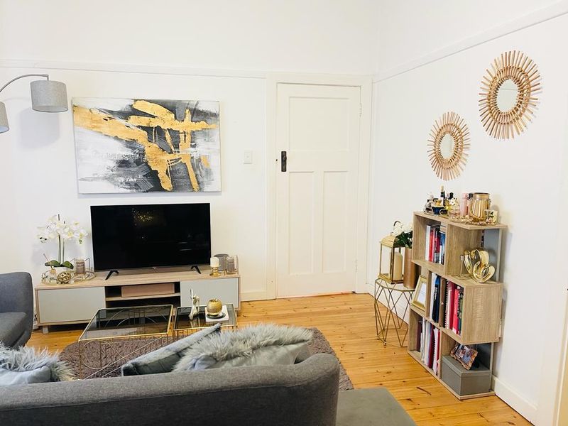A well-maintained living room featuring polished timber flooring, classic picture rails, and a traditional panelled door.