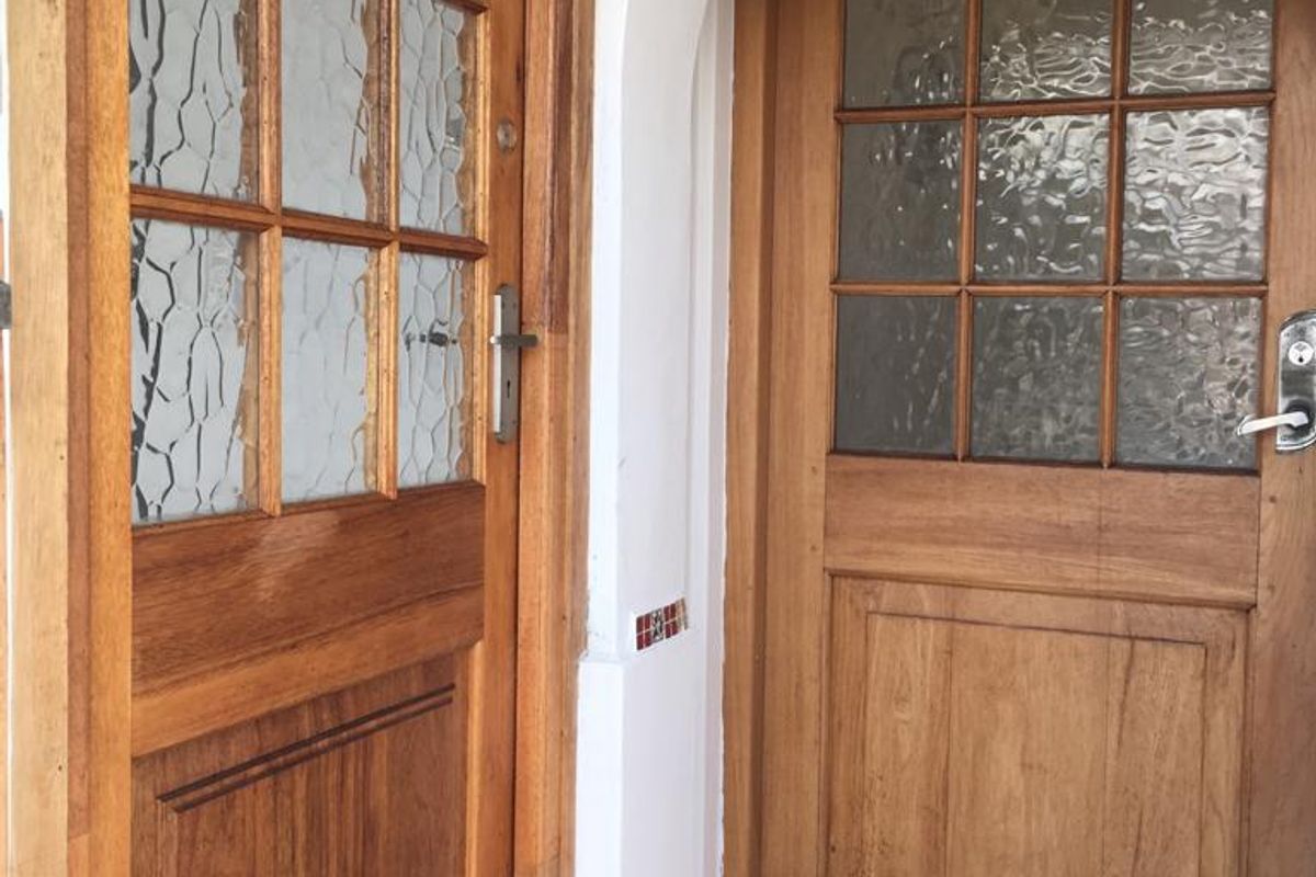Entrance area featuring two timber-framed glass panel doors set within an arched architectural frame and tiled flooring.
