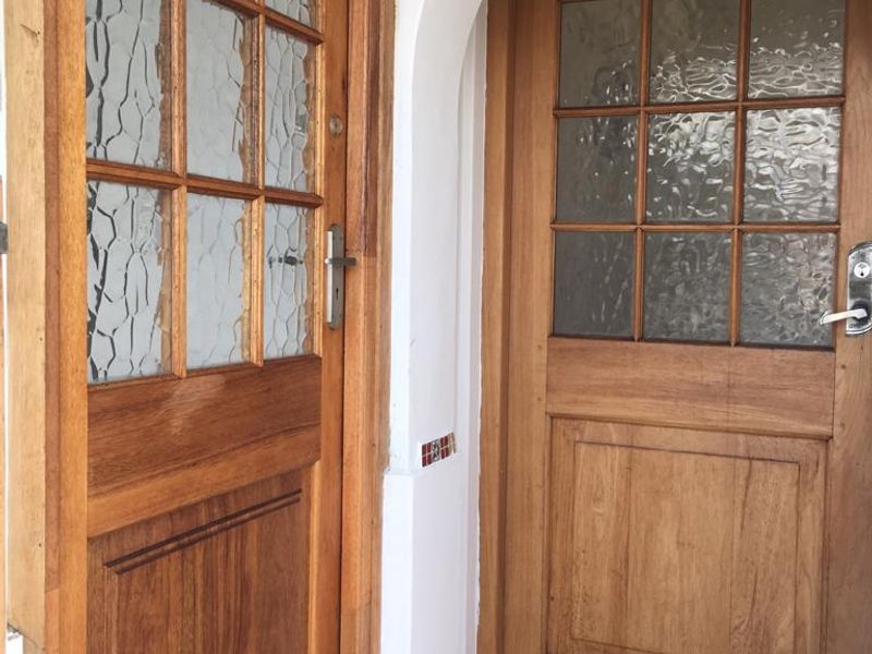 Entrance area featuring two timber-framed glass panel doors set within an arched architectural frame and tiled flooring.