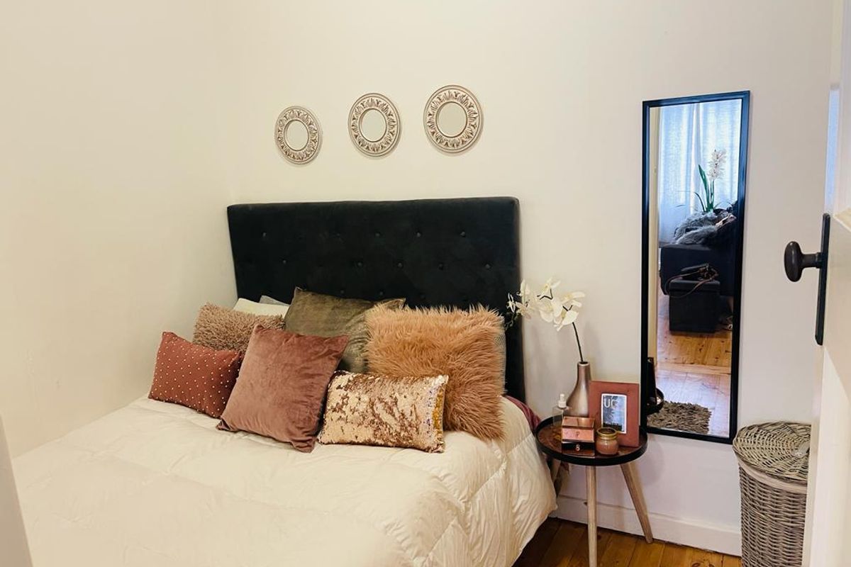 A cozy bedroom featuring warm hardwood flooring and a neutral wall finish, providing a comfortable and inviting sleeping space.