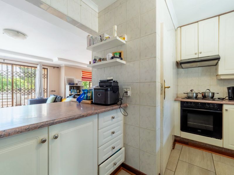 Open plan kitchen featuring built-in cabinetry, laminate countertops, and integrated oven with extractor fan, flowing into the adjacent living area.
