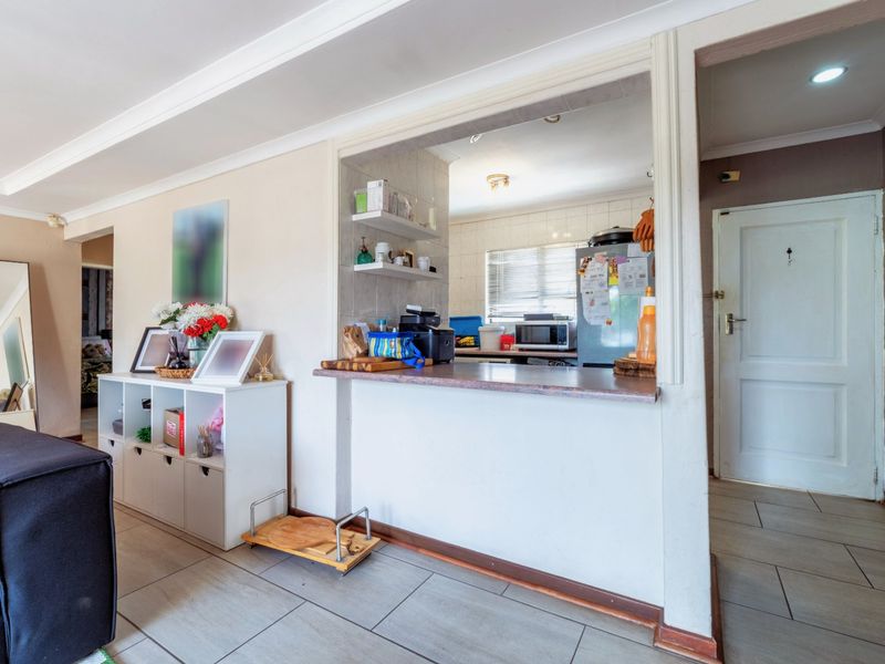 Open plan living area featuring a breakfast bar pass-through to the kitchen, tiled flooring, and coved ceiling details.