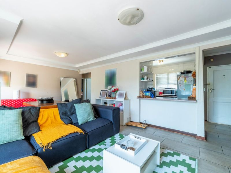 Open plan living area featuring tiled flooring, coved ceilings, and a convenient kitchen serving hatch connecting to the adjacent kitchen space.