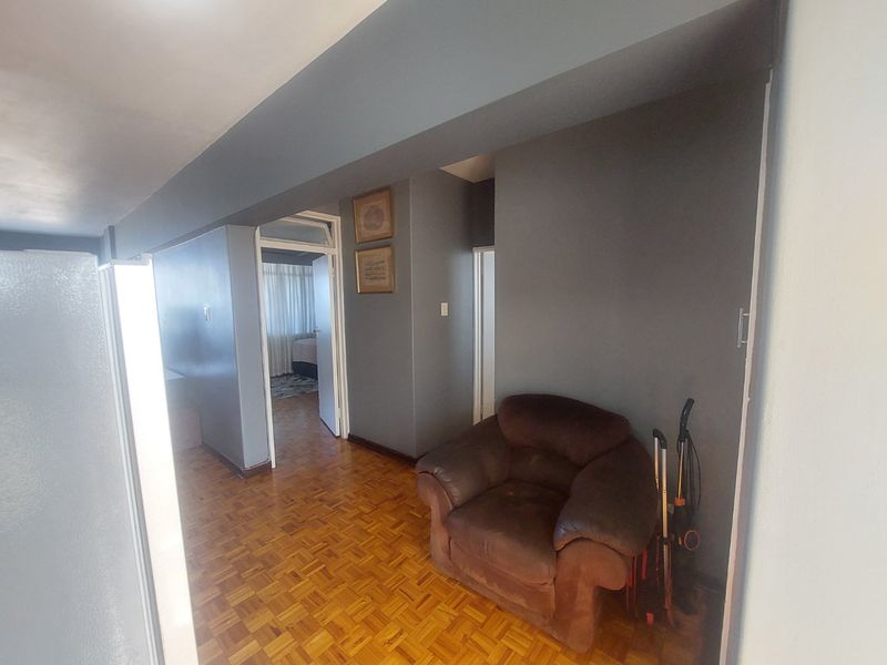 A hallway featuring classic parquet flooring and dark grey painted walls, providing access to adjacent rooms within the apartment.