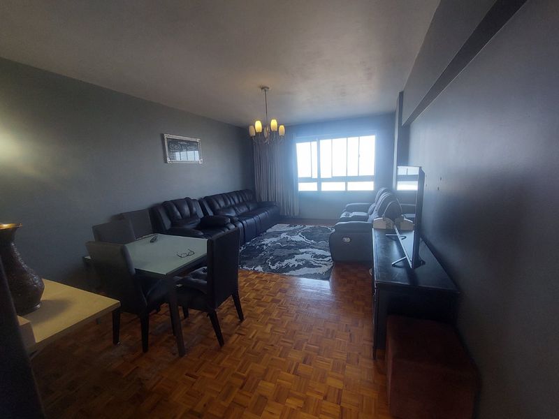 Open plan living and dining area featuring parquet flooring and large windows providing natural light.