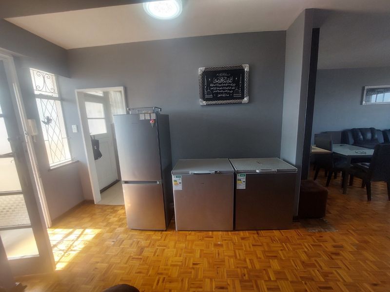 Open plan living area featuring classic parquet flooring and neutral grey walls, providing a versatile space that flows into the adjacent dining area.