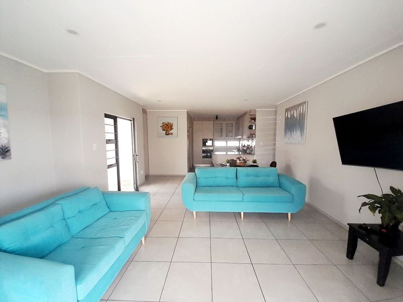 Spacious open-plan living area featuring neutral tiled flooring, recessed lighting, and a seamless transition to the kitchen space.