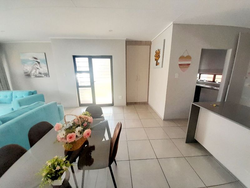 Open plan living and dining area featuring tiled floors, a kitchen island, and a sliding glass door leading to the exterior.
