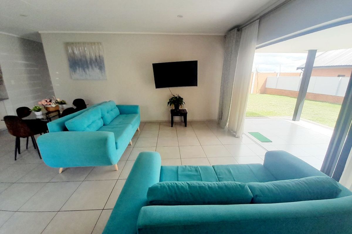 Bright living room featuring large format floor tiles and a wide sliding glass door providing seamless access to the outdoor patio and garden area.