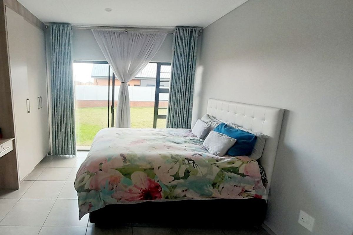 A well-maintained bedroom featuring tiled flooring, built-in cupboards, and a sliding glass door providing direct access to the garden.