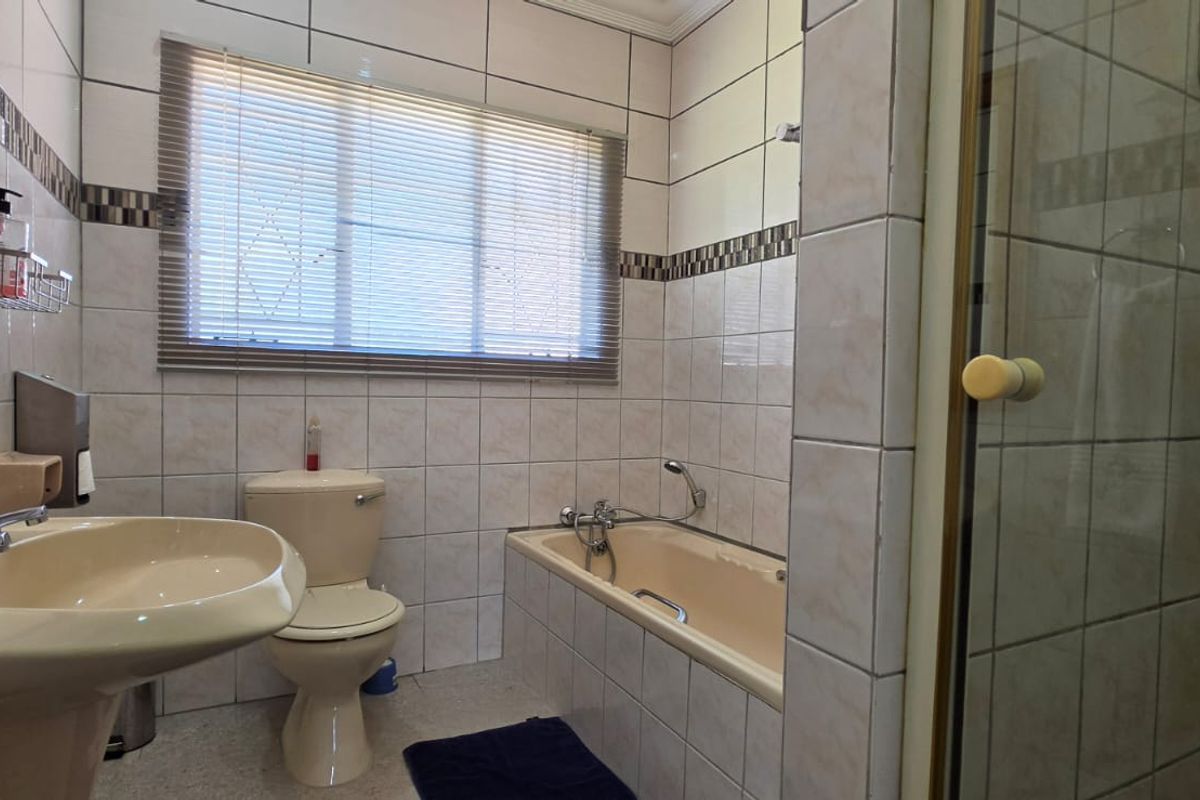 A functional bathroom featuring a pedestal basin, toilet, bathtub, and a separate shower enclosure with tiled walls.