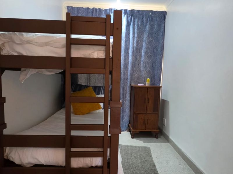 A compact bedroom featuring neutral walls, tiled flooring, and standard window treatments, suitable for a guest room or children's sleeping area.