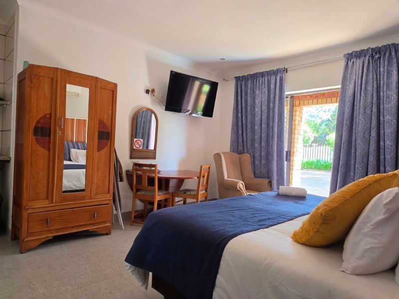 Open-plan studio unit featuring a kitchenette with sink, tiled flooring, and direct access to an outdoor area through sliding glass doors.