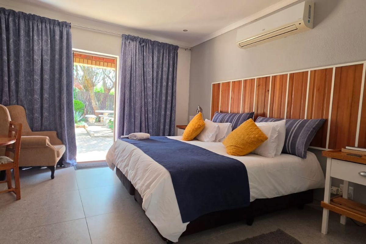 A well-maintained bedroom featuring tiled flooring, a split-system air conditioner, and direct access to an outdoor patio area through a sliding glass door.