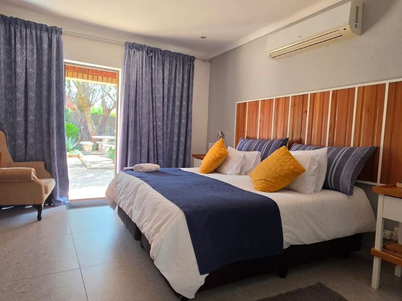 A well-maintained bedroom featuring tiled flooring, a split-system air conditioner, and direct access to an outdoor patio area through a sliding glass door.