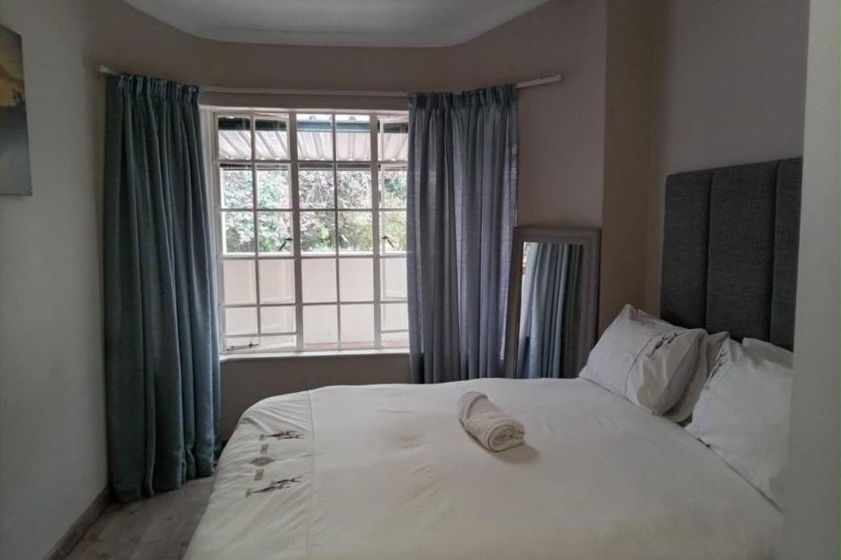 A cozy bedroom featuring a bay window, neutral wall tones, and laminate flooring, providing a comfortable and well-lit sleeping space.