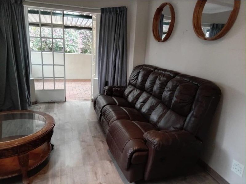 Living room featuring laminate flooring and direct access to a private brick-paved balcony through a sliding glass door.